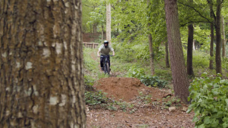 Slow-Motion-Shot-Of-Man-On-Mountain-Bike-Making-Mid-Air-Jumps-On-Dirt-Trail-Through-Woodland