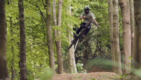 Zeitlupenaufnahme-Eines-Mannes-Auf-Dem-Mountainbike,-Der-In-Der-Luft-Auf-Einem-Feldweg-Durch-Den-Wald-Springt