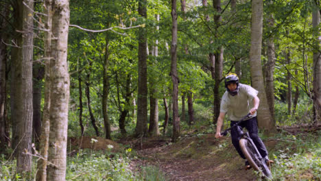 Slow-Motion-Shot-Of-Man-On-Mountain-Bike-Making-Mid-Air-Jumps-On-Dirt-Trail-Through-Woodland-3