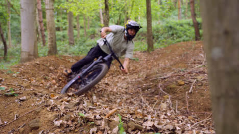 Slow-Motion-Shot-Of-Man-On-Mountain-Bike-Cycling-Along-Trail-Through-Woodland