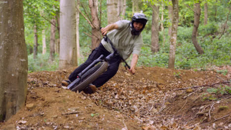 Slow-Motion-Shot-Of-Man-On-Mountain-Bike-Cycling-Along-Trail-Through-Woodland-