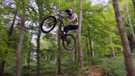 Slow-Motion-Shot-Of-Man-On-Mountain-Bike-Making-Mid-Air-Jumps-On-Dirt-Trail-Through-Woodland-8