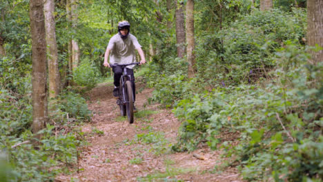 Slow-Motion-Shot-Of-Man-On-Mountain-Bike-Cycling-Along-Trail-Through-Woodland--