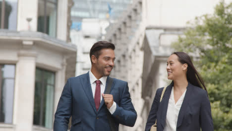 Businesswoman-And-Businessman-Walking-Along-Street-In-City-Of-London-Together-Talking