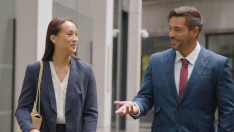 Businesswoman-And-Businessman-Walking-Along-Street-In-City-Of-London-Together-Talking-1