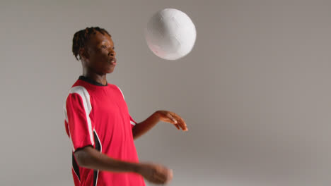 Studio-Shot-Of-Young-Male-Footballer-Wearing-Club-Kit-Controlling-Ball-With-Chest-And-Passing