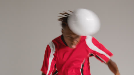 Young-Male-Footballer-In-Studio-Running-and-Heading-Ball-