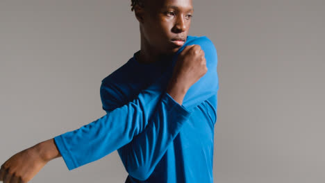 Studio-Shot-Of-Young-Male-Footballer-Warming-Up-With-Stretches-Before-Game