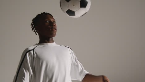 Studio-Shot-Of-Young-Male-Footballer-Wearing-Club-Kit-Controlling-Ball-With-Chest-And-Shooting