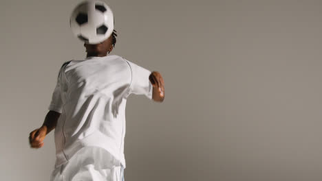 Studio-Shot-Of-Young-Male-Footballer-Wearing-Club-Kit-Controlling-Ball-With-Chest-And-Passing-2
