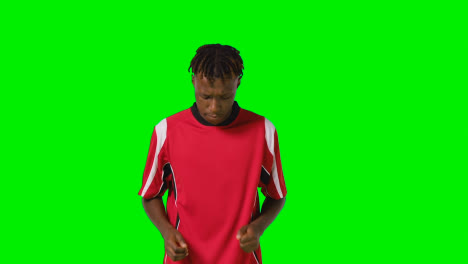 Studio-Shot-Of-Young-Male-Footballer-Warming-Up-With-Exercises-Before-Game-Against-Green-Screen