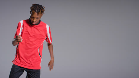 Studio-Shot-Of-Young-Male-Footballer-Wearing-Club-Kit-Controlling-Ball-With-Chest-And-Passing-3