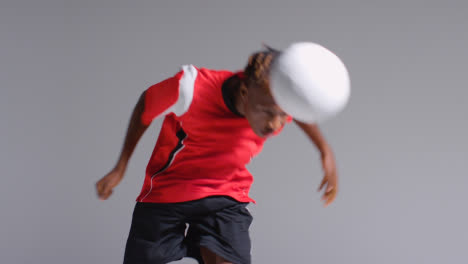 Young-Male-Footballer-In-Studio-Running-and-Heading-Ball-1