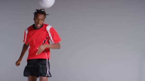 Young-Male-Footballer-In-Studio-Running-and-Heading-Ball-2