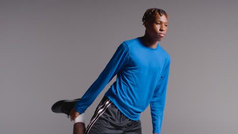 Studio-Shot-Of-Young-Male-Footballer-Warming-Up-With-Stretches-Before-Game-4