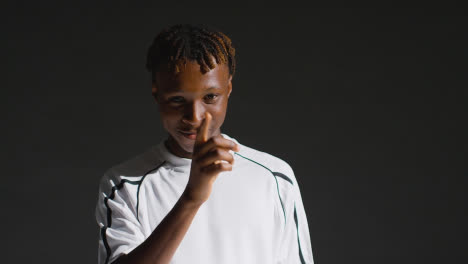Low-Key-Studio-Portrait-Of-Young-Male-Footballer-Wearing-Club-Kit-Counting-To-Five-On-Fingers