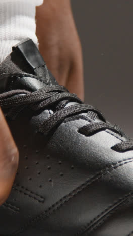 Vertical-Video-Close-Up-Of-Male-Footballer-Or-Sportsperson-Tying-Laces-On-Boots-Or-Training-Shoes-