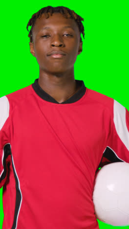 Vertical-Video-Studio-Portrait-Of-Male-Footballer-Wearing-Club-Kit-With-Ball-Under-Arm-Against-Green-Screen-1