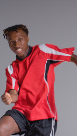 Vertical-Video-Of-Young-Male-Footballer-In-Studio-Running-and-Heading-Ball-