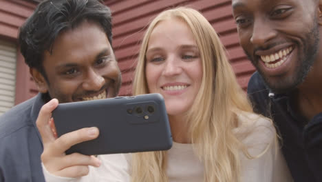 Multi-Cultural-Friends-Celebrating-Watching-Sports-Game-On-Mobile-Phone-Outdoors-Together-2