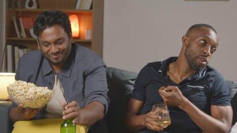 Amigos-Multiculturales-Sentados-En-El-Sofá-En-Casa-Viendo-La-Televisión-Comiendo-Palomitas-De-Maíz-1