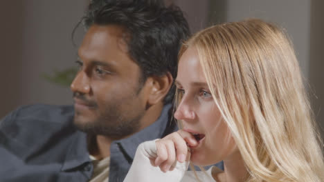 Amigos-Multiculturales-Sentados-En-Un-Sofá-En-Casa-Viendo-La-Televisión-Juntos