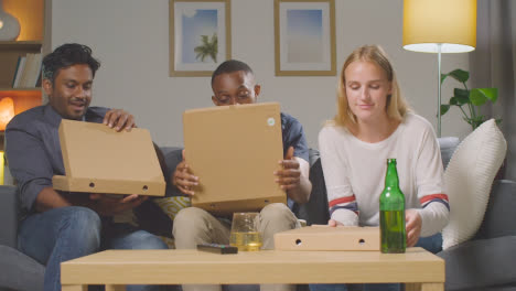 Multi-Cultural-Friends-Sitting-On-Sofa-At-Home-Eating-Takeaway-Pizza-Delivery-And-Drinking-Beer-2