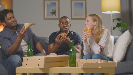 Multi-Cultural-Friends-Sitting-On-Sofa-At-Home-Eating-Takeaway-Pizza-Delivery-And-Drinking-Beer-3