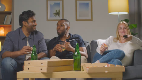 Multi-Cultural-Friends-Sitting-On-Sofa-At-Home-Watching-TV-Eating-Takeaway-Pizza-Delivery-5