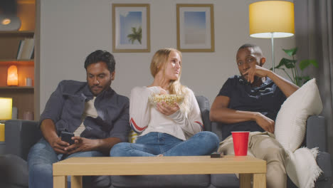 Multi-Cultural-Friends-Sitting-On-Sofa-At-Home-Watching-TV-Horror-Movie-And-Eating-Popcorn-6