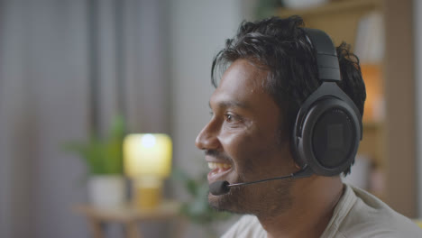 Man-Wearing-Headset-Sitting-On-Sofa-At-Home-Gaming-Online-14