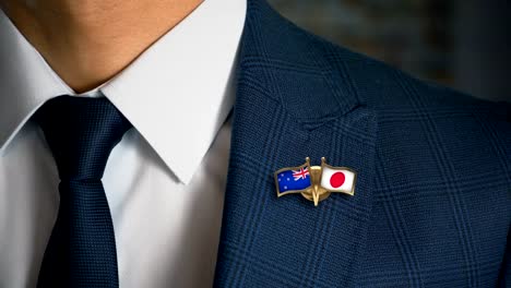 Geschäftsmann-zu-Fuß-in-Richtung-Kamera-mit-Freund-Land-Flaggen-Pin-Neuseeland---Japan