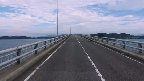 Ozean-\"Tsunoshima-Brücke\"-Schuss-leer,-gerade-Straße-überfahren