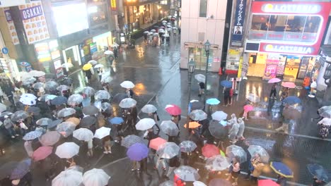Crowd-of-people-walking-with-umbrellas-while-raining-on-Dotonbori-Street,-Osaka,-Japan