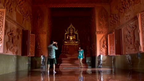 Un-hombre-es-fotografiar-a-una-mujer-en-un-smartphone-por-una-estatua-de-Buda-en-un-templo-budista