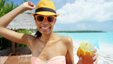 Sonriendo-étnica-mujer-cóctel-colorido-disfrutando-en-la-playa