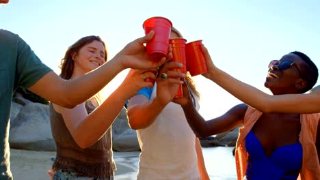 Grupo-de-amigos-tostado-vasos-de-cerveza-en-la-playa-4k