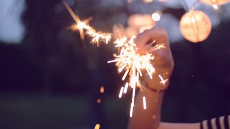 slow-motion-shot-of-young-woman-lighting-sparklers-in-garden