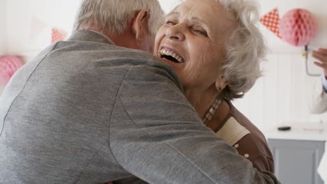 Smiling-Senior-Woman-Embracing-Male-Friend-at-Birthday-Celebration