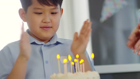 Asia-muchacho-soplando-las-velas-en-el-pastel-de-cumpleaños