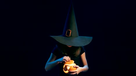 Girl-wearing-black-witch-hat-holding-jack-o'-lanterns