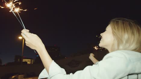 Young-hipster-girl-friends-having-fun-running-with-sparklers-and-smoke-grenade-and-night-with-shopping-cart