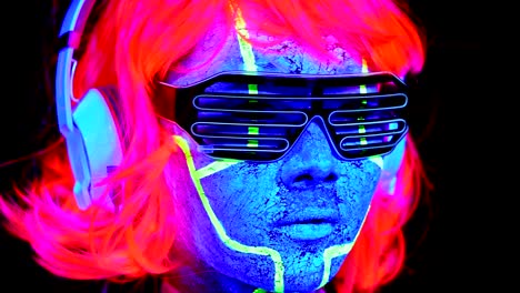 Woman-with-UV-cyborg-face-paint,-wig,-glowing-glasses,-clothing-with-headphones-close-up-face-shot.-Asian-woman.-.