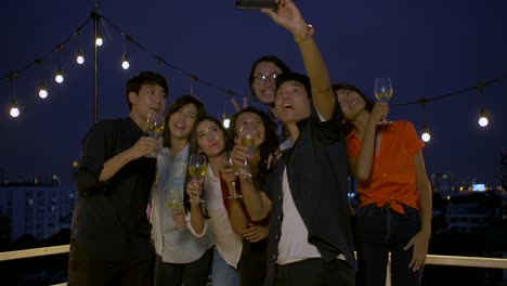 Group-of-young-friends-dancing-and-having-fun-celebrating-New-Year-and-Christmas-Festival-together-at-summer-rooftop-party.-Slow-motion.