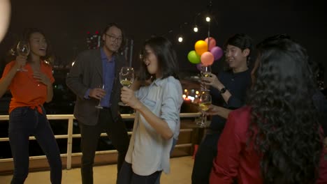 Group-of-young-friends-dancing-and-having-fun-celebrating-New-Year-and-Christmas-Festival-together-at-summer-rooftop-party.-Slow-motion.