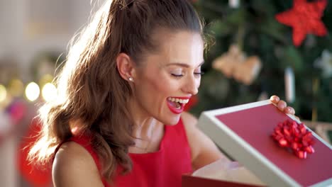 happy-young-woman-near-Christmas-tree-opening-Christmas-gift