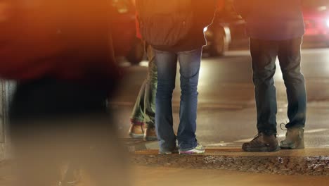 Anonymous-people-waiting-to-cross-street-during-city-urban-atmosphere-at-night