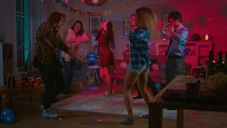 En-el-College-House-Party:-grupo-diverso-de-amigos-divertirse,-bailar-y-socializar.-Chicos-y-chicas-bailando-en-el-círculo.-Disco-estroboscópico-neones-iluminando-la-habitación.