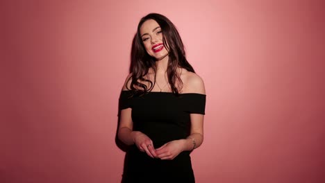 Brunette-happy-woman-laughing-with-confetti-in-pink-background-wear-red-dress