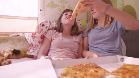 Girl-joking-and-feeding-her-friend-huge-slice-of-pizza